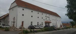 a large white building with cars parked in front of it at Panská sýpka in Sedlec