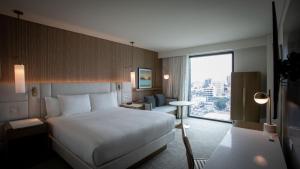 une chambre d'hôtel avec un lit et une grande fenêtre dans l'établissement Courtyard by Marriott Santo Domingo Piantini, à Saint-Domingue