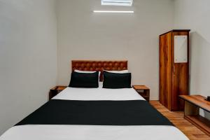 OYO Flagship Hotel Blue Moon في باتنا: غرفة نوم مع سرير كبير مع وسائد سوداء