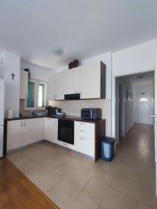 a kitchen with white cabinets and a tile floor at Apartman Elephant in Postira