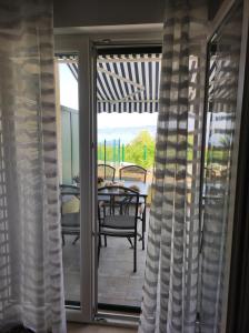 une porte coulissante en verre avec une table et des chaises sur la terrasse. dans l'établissement Apartman Elephant, à Postira