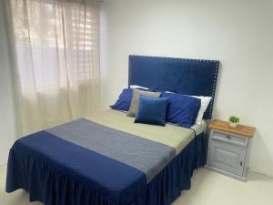 Schlafzimmer mit einem Bett mit blauer Bettwäsche und Kissen in der Unterkunft Suite Jacarandas 103 in Guadalajara