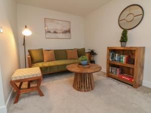 a living room with a green couch and a table at Reubens Cottage in Barnstaple