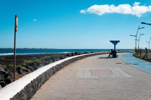 a stone wall next to a beach with the ocean at Jable 6 - Waterfront Luxury Apartment in Corralejo