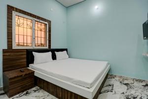 uma cama branca num quarto com uma janela em Super OYO Shivansh banquet and hotel em Dhanbad