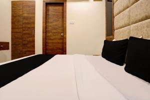 a bedroom with a large white bed with black pillows at OYO Flagship Hotel Ashirwad Inn in Mumbai