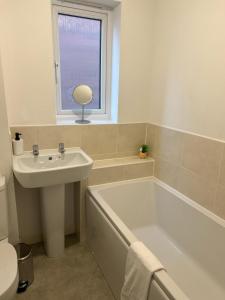 uma casa de banho com um lavatório, uma banheira e uma janela. em Village House Cardiff - Close to A48 and M4 em Cardiff