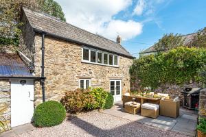 an exterior view of a stone house with a patio at Moonrakers in Malborough