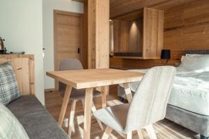 a wooden table and chairs in a room with a bed at Vivi Suites&Spa Molveno in Molveno
