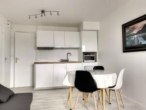 a kitchen with white cabinets and a table and chairs at 106 - Appartement rénové Sables d'Or Les Pins in Fréhel