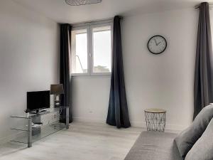 a living room with a couch and a clock on a wall at 106 - Appartement rénové Sables d'Or Les Pins in Fréhel