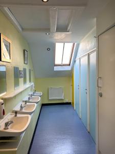 un baño con una fila de lavabos y una ventana en Castle Rock Hostel - Adults Only, en Edimburgo