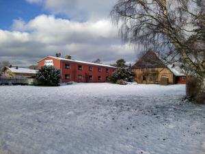 a red building with snow in front of it at Pension Stocker in Dierhagen