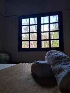 1 dormitorio con cama y ventana con toalla en hotel fazenda das montanhas, en Delfim Moreira