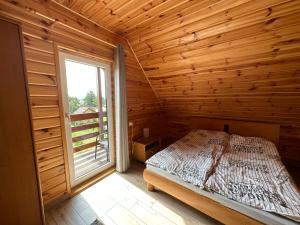 a bedroom with a bed in a wooden room with a window at Rajska Przystań II in Wrony