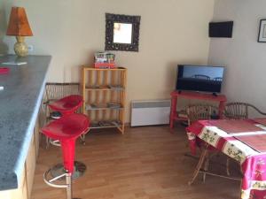Sala de estar con taburetes rojos y TV en Maison En Pierres Proche Agnac en Firmi