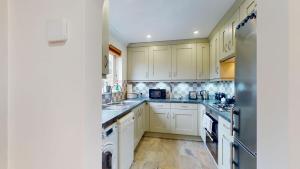 a kitchen with white cabinets and a refrigerator at Cherry Tree Cottage in Bicester