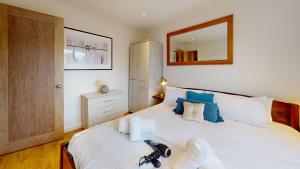 um quarto com uma grande cama branca com almofadas azuis em Cherry Tree Cottage em Bicester
