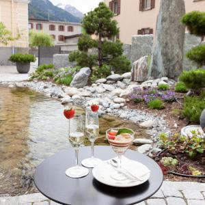 deux verres de vin sur une table à côté d'une rivière dans l'établissement Hotel Baer & Post Zernez, à Zernez