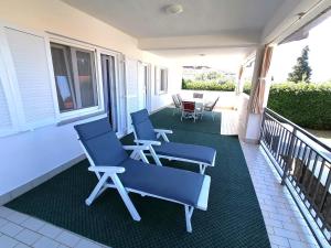 a porch with two blue chairs on a balcony at APARTMAN GLORIA in Krk