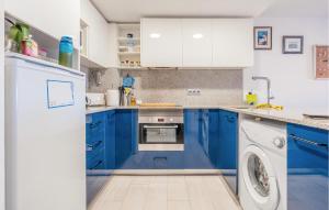 cocina azul con armarios blancos y lavadora en 2 Bedroom Lovely Apartment In L'escala, en L'Escala
