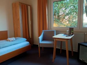 een slaapkamer met een bed, een stoel en een tafel bij Pension Stocker in Dierhagen