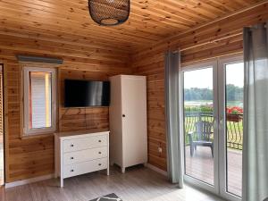 a room with a tv and a dresser with a television in it at Rajska Przystań II in Wrony