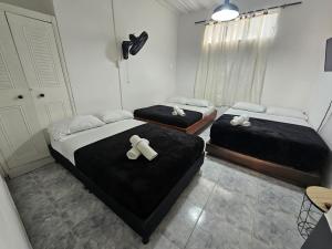 three beds in a room with black sheets at Acogedor Apartamento En La Circunvalar By Parceros Group in Pereira