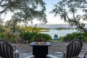 two chairs and a table next to a lake at 3 Story Haven Fire Pit kayaks updated 360 Views in Cedar Key
