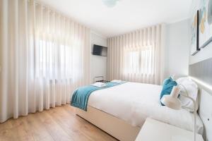 a white bedroom with a bed and windows at Casa de Eiró by House and People in Barcelos