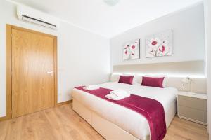 a white bedroom with a large bed and a wooden door at Casa de Eiró by House and People in Barcelos