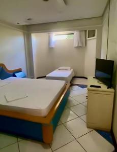 um quarto de hospital com duas camas e uma televisão em Villa do Lago em Poços de Caldas