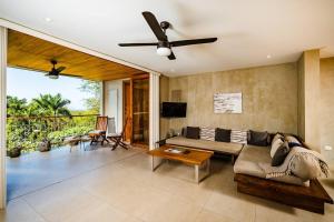ein Wohnzimmer mit einer Couch und einem Deckenventilator in der Unterkunft Spacious & Serene With Partial Ocean & Jungle View in Tamarindo