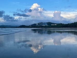 eine Spiegelung von Wolken im Wasser an einem Strand in der Unterkunft Spacious & Serene With Partial Ocean & Jungle View in Tamarindo