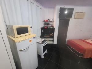 Kleines Zimmer mit einer Mikrowelle auf dem Kühlschrank in der Unterkunft Hospedaria cmc unidade 03 Com Estacionamento in Riacho Fundo