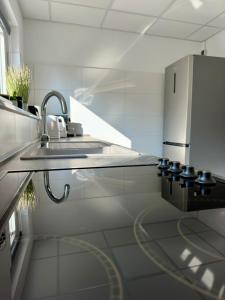 a white kitchen with a sink and a refrigerator at renovierte & voll möblierte Wohnung für 7 Personen in Minden
