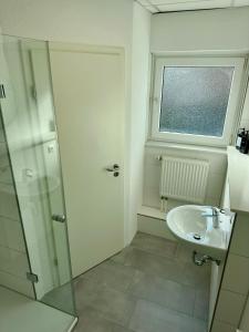 a bathroom with a sink and a glass shower door at renovierte & voll möblierte Wohnung für 7 Personen in Minden