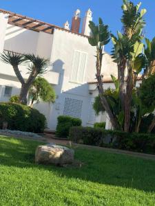 una casa blanca con palmeras y una roca en La Casita de Marina Golf-Costa Ballena, en Cádiz