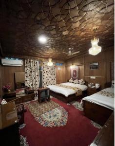 a bedroom with two beds and a tv on a red rug at Lakes Crown Group Of Houseboats in Srinagar