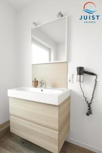 a bathroom with a white sink and a mirror at Landhaus Gertrude 105 - Wohnung Wattenmeer in Juist