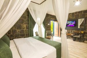 um quarto com uma cama com cortinas e uma televisão em STONE VILLAGE em Trabzon