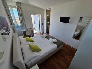 B&B White con Parcheggio Privato في بورتو سيساريو: غرفة نوم بسرير ابيض كبير مع مخدات خضراء