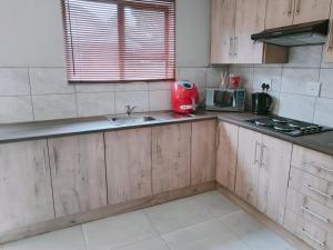 une cuisine avec un évier et un appareil rouge dans l'établissement Reutlwane Gardens Apartments, à Secunda