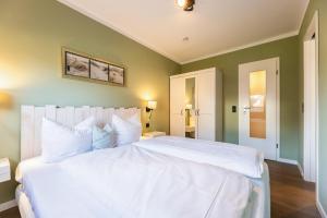 a large white bed in a bedroom with green walls at Appartement Hamburg in Westerland