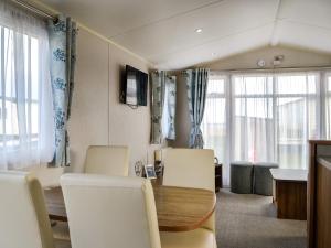 a dining room with a table and chairs and windows at Sea View 59 - Uk45586 in Mainsriddle