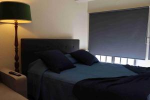a bedroom with a blue bed with a lamp at Apartamento T1 do Patrão in Sabugueiro
