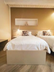 a bedroom with two beds with white sheets at GIO' HOUSE in Fossano