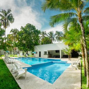una piscina con sillas blancas y palmeras en amaremar, en San Luis La Herradura
