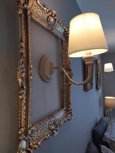 an ornate gold mirror hanging on a wall with a lamp at Le mas de Roussillon chambre d'hôtes in Roussillon