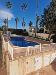 a fence around a swimming pool with palm trees at Scenic View Studio With Terrace in Torrevieja